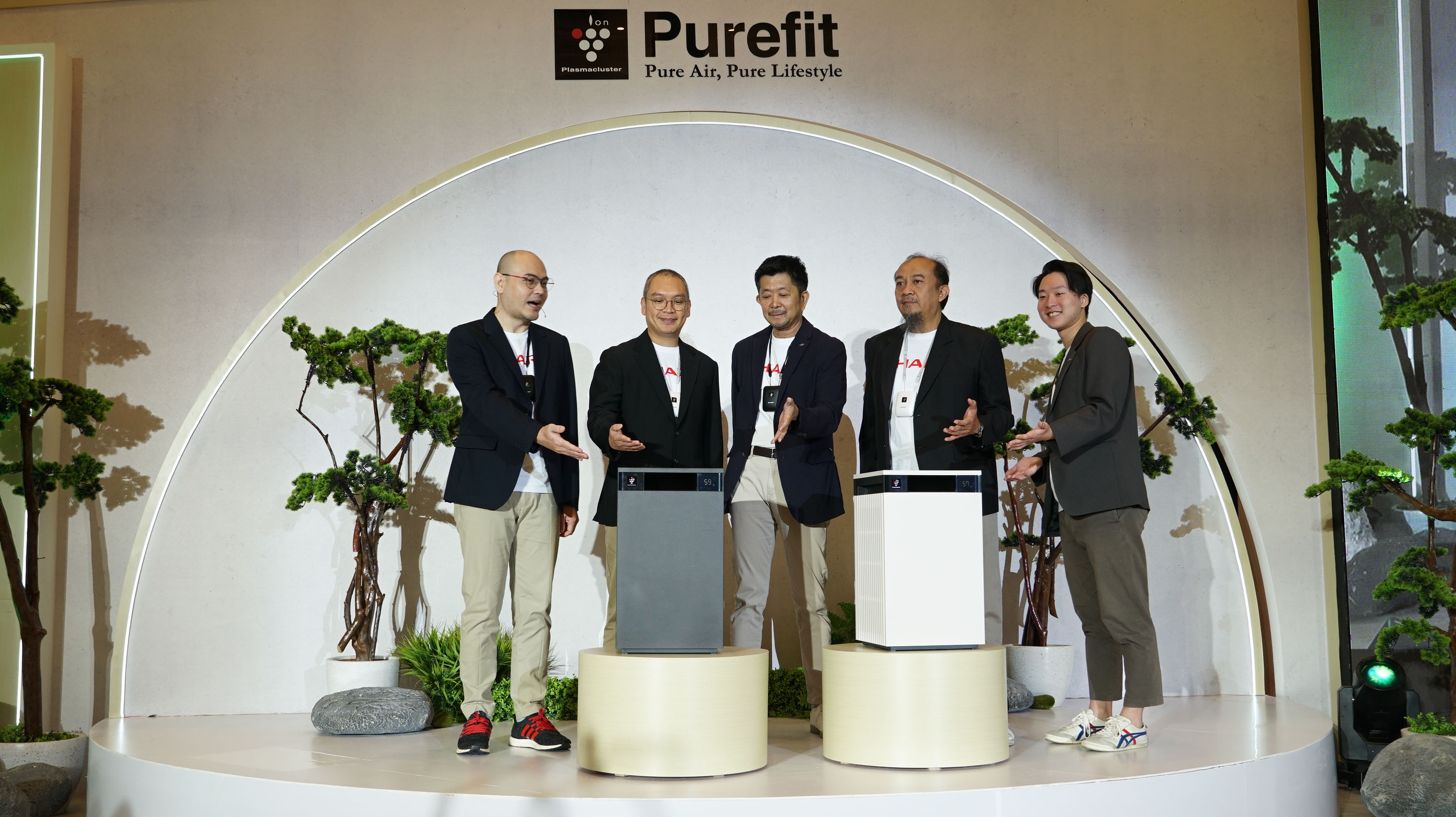  Four men in suits standing on a stage in front of a large Sharp Purefit MiniSeries air purifier.